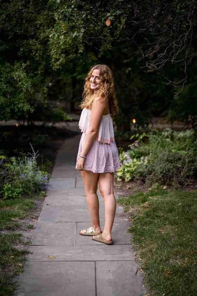 Girl in a pink strapless dress walking away, looking back over her left shoulder.