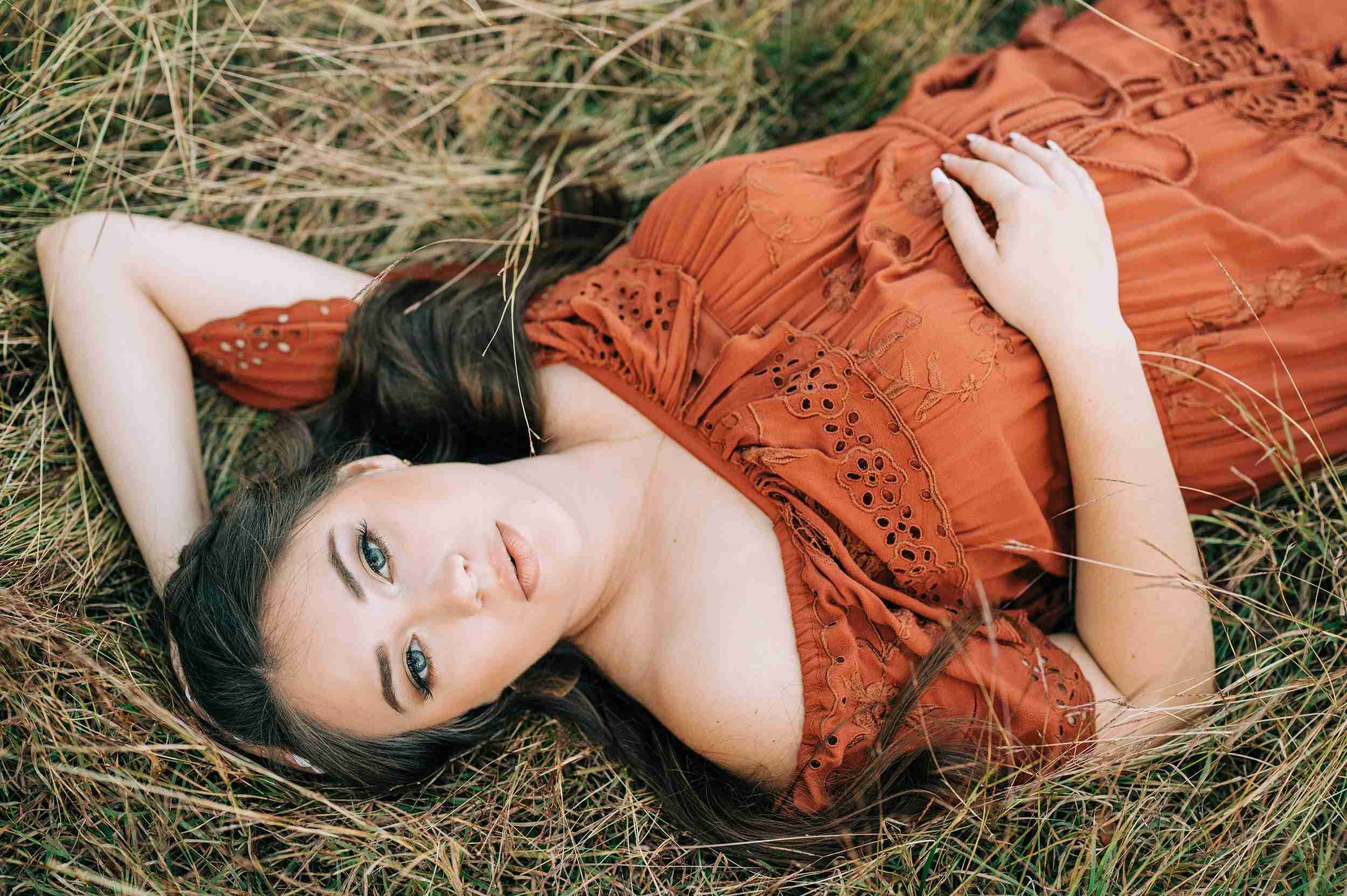 High school senior laying in the grass looking at the camera