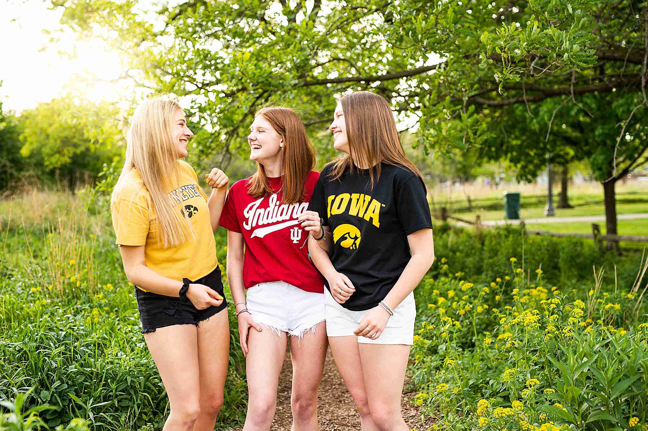 Three female high school graduates wearing their college t-shirts laughing and having fun.