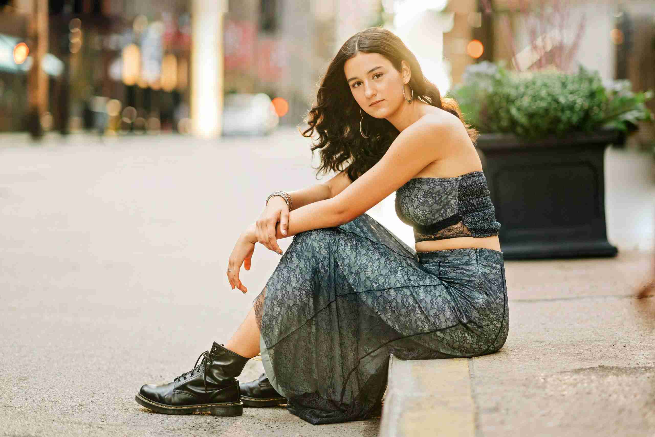 girl long black hair sitting on street curb