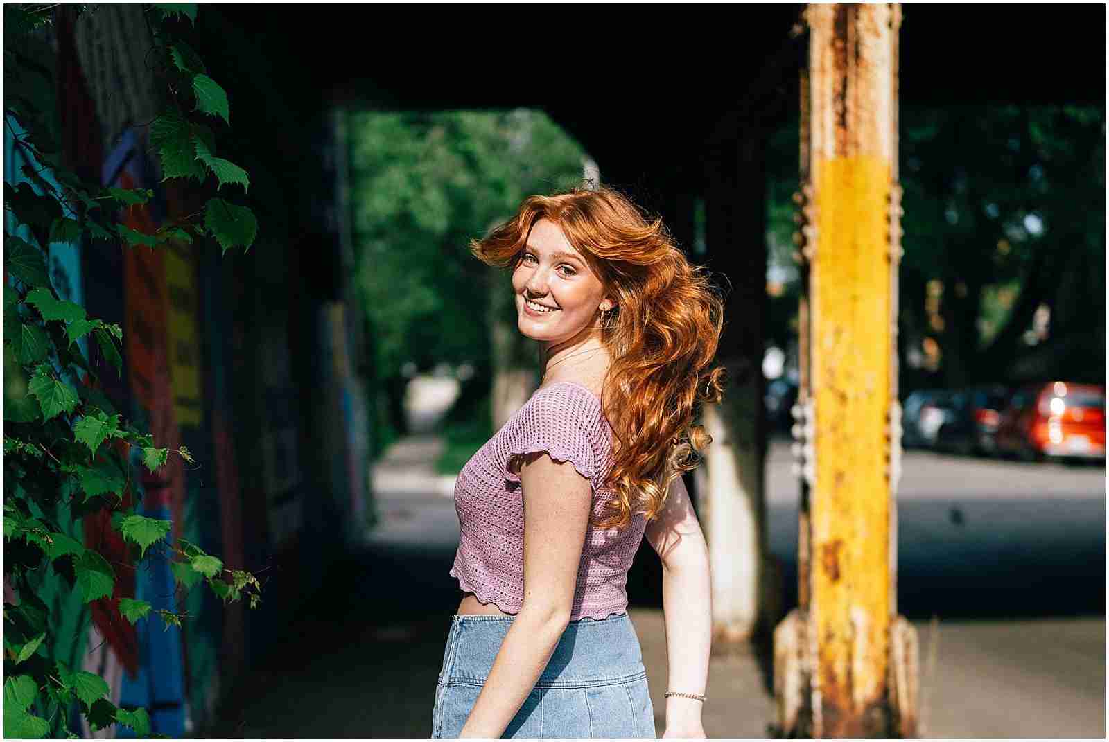 Four Reasons to Book a Senior Session - girl wearing purple shirt and denim skirt skipping and looking back at camera - award-winning Chicago senior photographer Shalimar B. Photography.