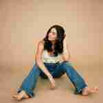 What to Ask Your Senior Photographer Before Booking – senior girl wearing white crochet top sitting on brown studio backdrop – award-winning Chicago senior photographer Shalimar B. Photography.